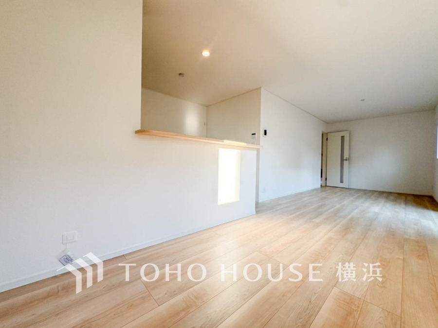 明るい光が差し込む、ナチュラルな木目調フローリングの広々としたリビング空間です。