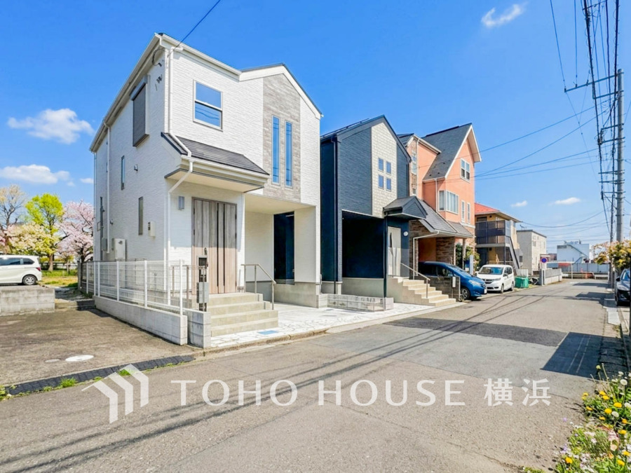 青空の下、モダンなデザインの新築一戸建てが並ぶ閑静な住宅街の風景です。