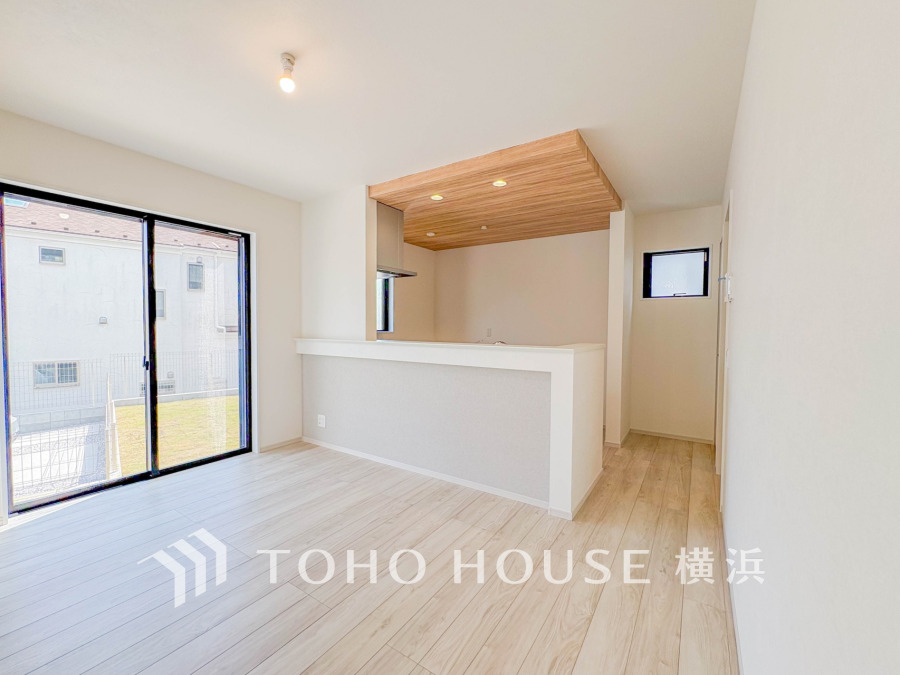 明るい光が差し込むリビングダイニング。木目天井がアクセントの対面キッチンで開放感と温かみのある空間です。