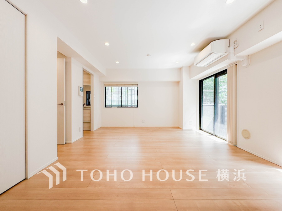 明るい光が差し込む広々としたリビング。ナチュラルな木目床と白壁が落ち着いた空間を演出しています。