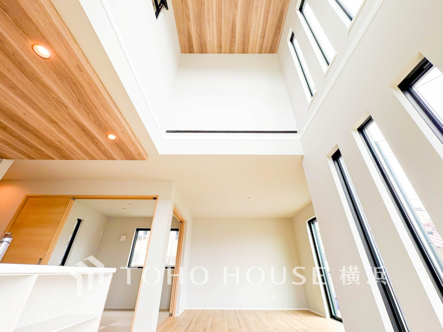 大きな窓と吹き抜けで開放感あふれるリビング。木目天井が温かみを演出します。
