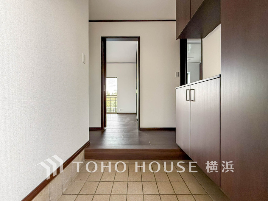 落ち着いた色調の収納付き玄関。段差で室内と区切られ、清潔感と使いやすさを両立しています。